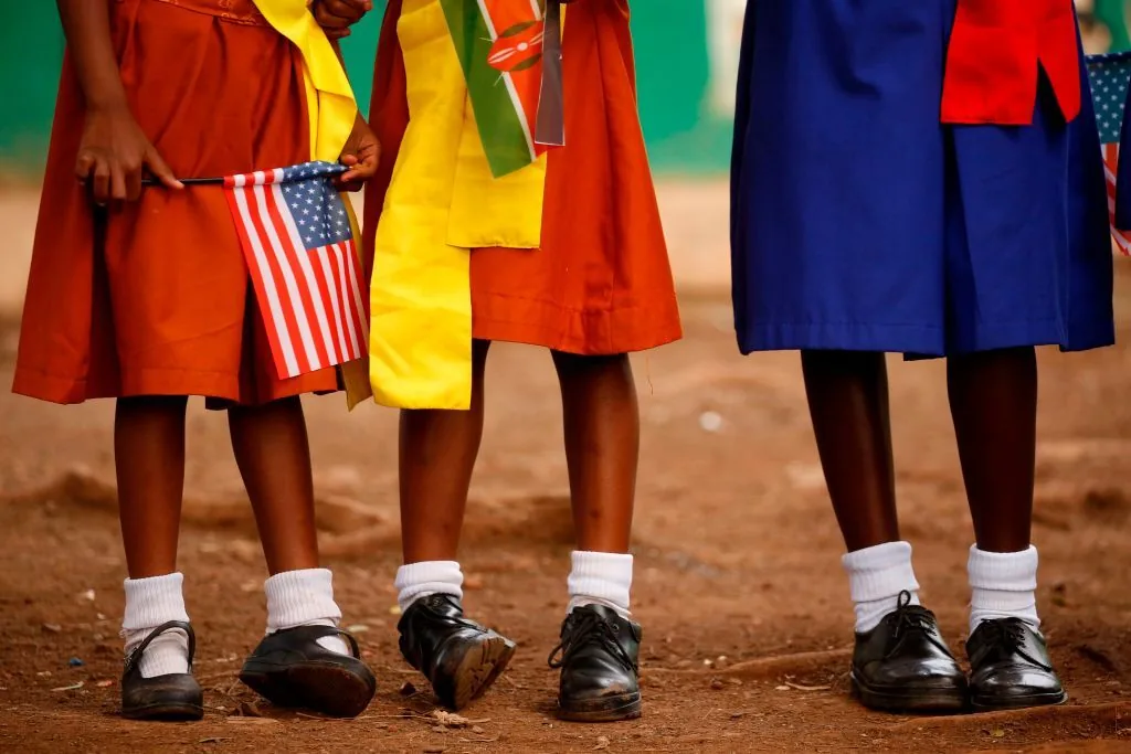 Girls with U.S. and Kenyan flags waiting to greet the U.S. ambassador at a PEPFAR girls' empowerment project in Nairobi